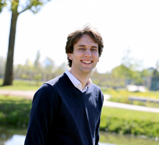 Jarno buiten lachend, boom in achtergrond.