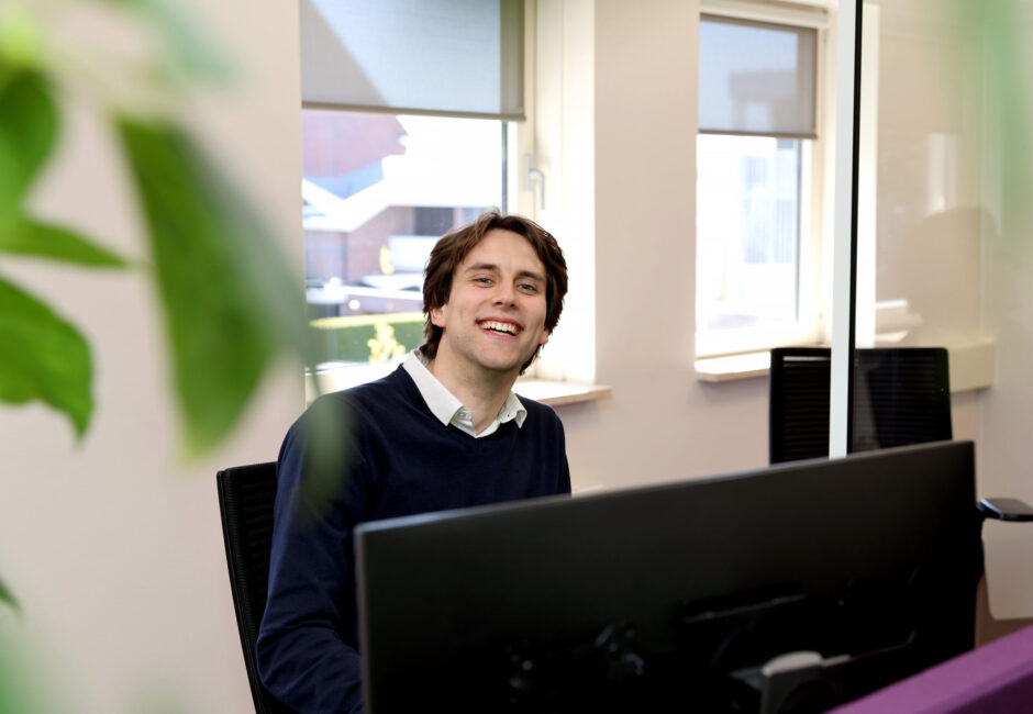 Jarno lachend achter bureau.