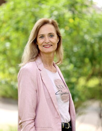 Jeanine lachend naar de camera voor een loofboom.