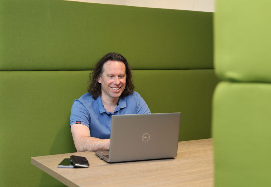 Steven aan het werk achter computer, twee telefoons binnen handbereik.